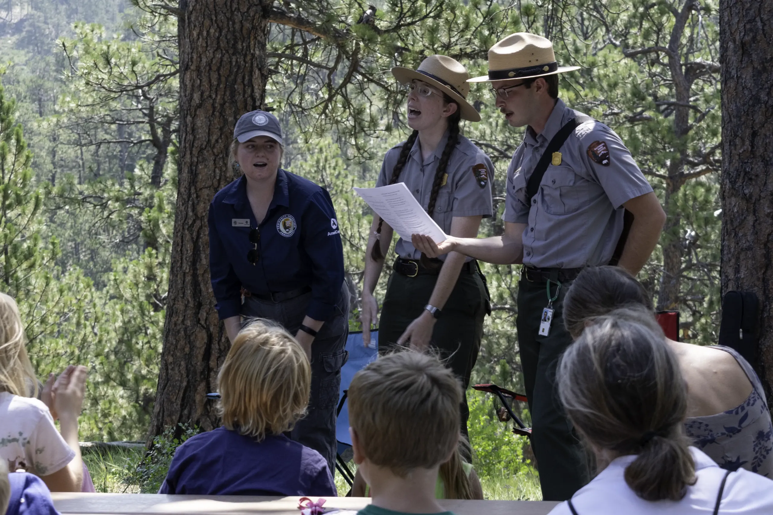 Park educators lead an outdoor activity for families among pine trees